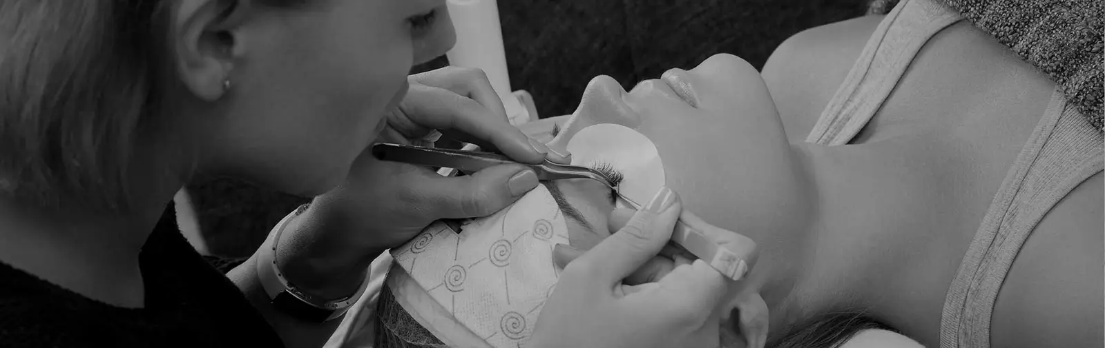 Lash artist applying eyelash extensions with tweezers at Lashes by Lexi