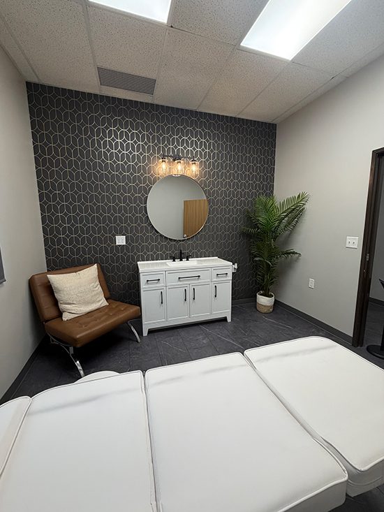 Lashes by Lexi studio — lash bed facing the black and gold accent wall with vanity and mirror